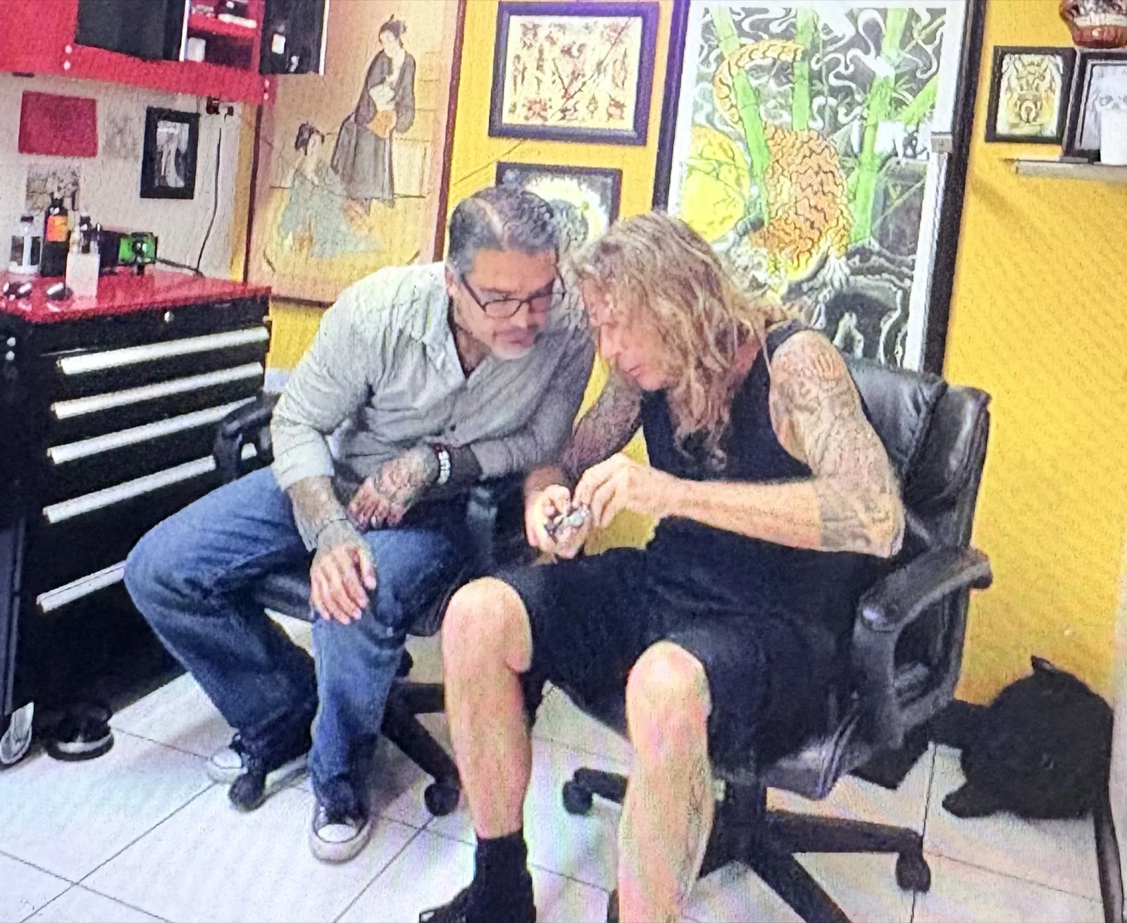 Kevin Mokuahi and Mike Hatfield in a tattoo studio looking at equipment together