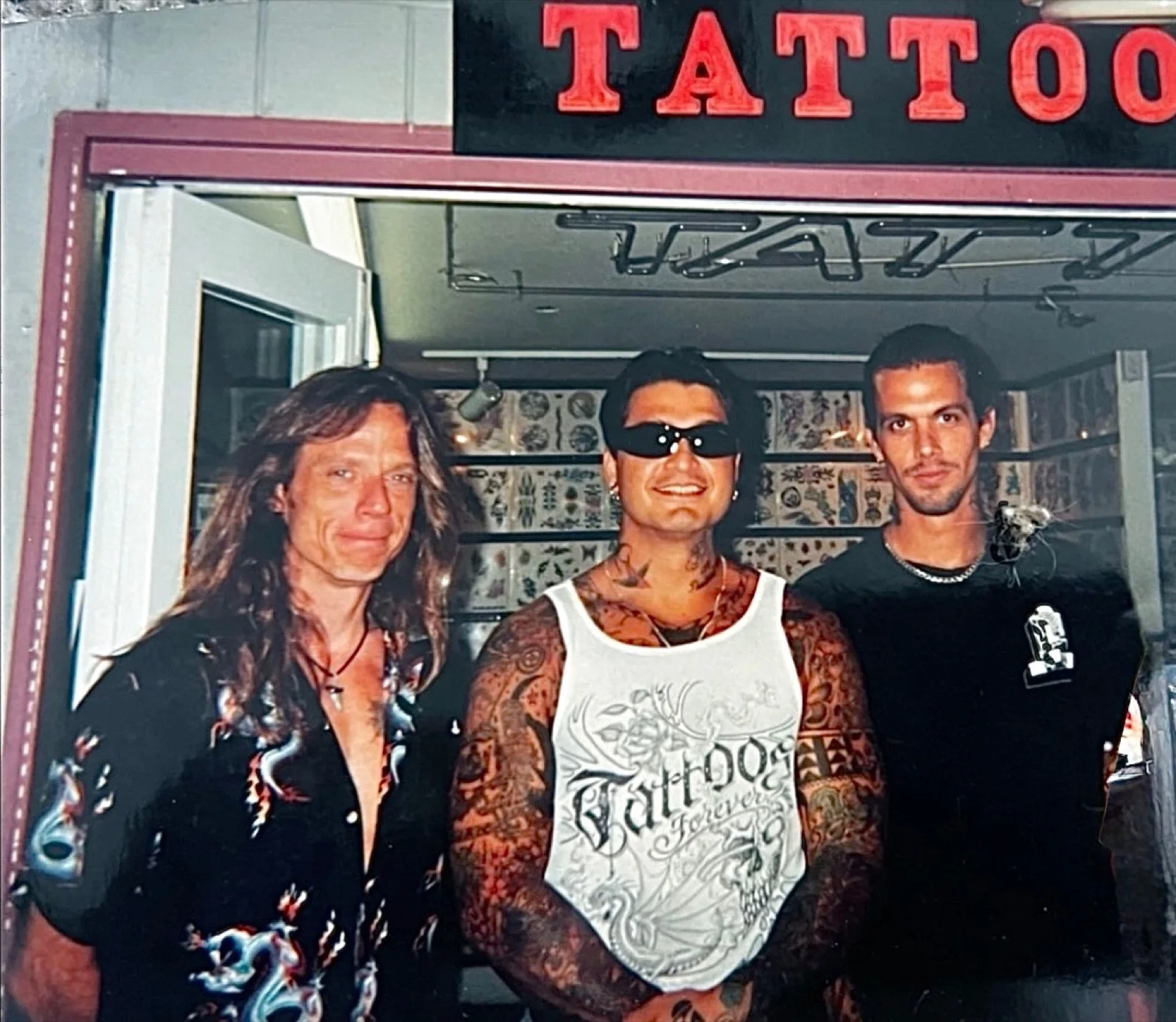 Mike Hatfield, Kevin Mokuahi, and Mark Claunch — three Honolulu tattooers under the TATTOO neon at the original Aloha Tattoo, upstairs from where Sacred Art is located today