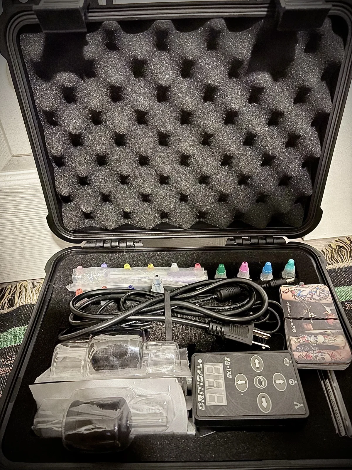 Kevin Mokuahi's tattoo kit — power supply, ink caps, RCA cord, cartridge needles foam-padded inside a Pelican case